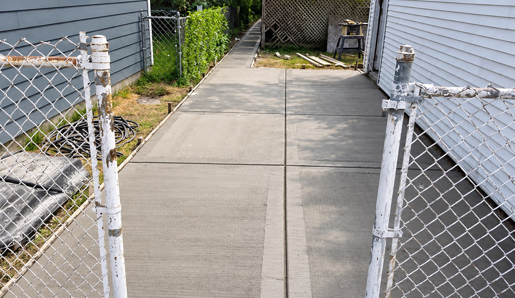 Finished narrow concrete walkway between a home and fence