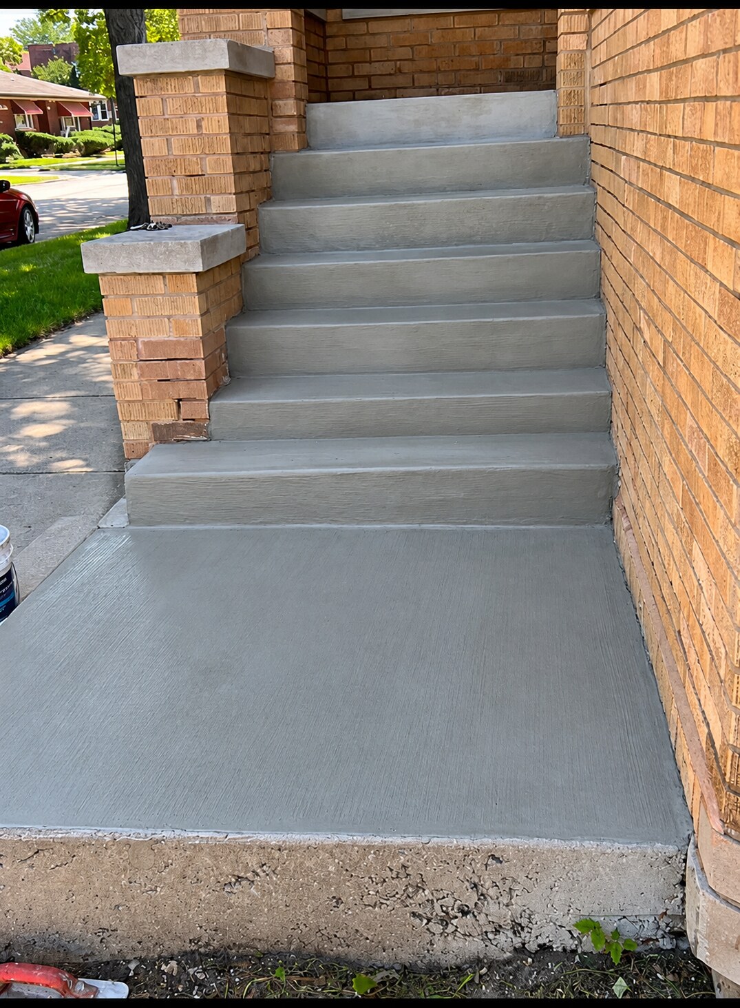 Concrete entry steps and landing alongside brickwork